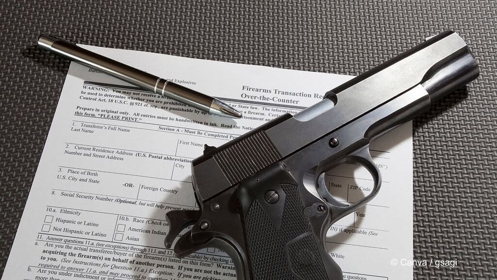 Eine Pistole liegt auf einem Formular zum Tragen von Schusswaffen. Oben links liegt auch ein Kugelschreiber.