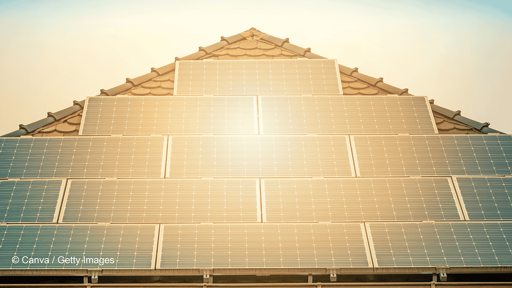 Ein dreieckiges Dach mit Photovoltaikanlage. In den Solarpanelen spiegelt sich die Sonne und erzeugt eine angenehme Stimmung.