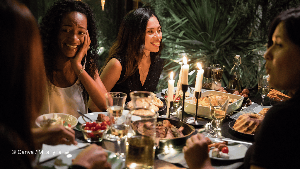 In dunkler, gemütlicher Atmosphäre sitzen mindestens vier Frauen um einen Tisch drum herum. Auf dem Tisch stehen ein Kerzenständer und verschiedene Gerichte, wie Fleisch, und ein Kuchen, aber auch Sektgläser. Die Szene soll an eine Weihnachtsfeier mit Kolleginnen und Kollegen erinnern.