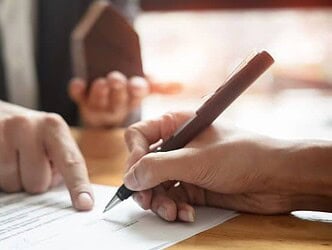 Person zeigt auf Papier und andere Person hält Stift in der Hand