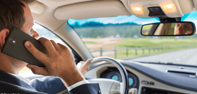 Ein Mann telefoniert mit seinem Handy am Ohr, während er Autofährt: Die Handynutzung beim Autofahren kann 100 € kosten.
