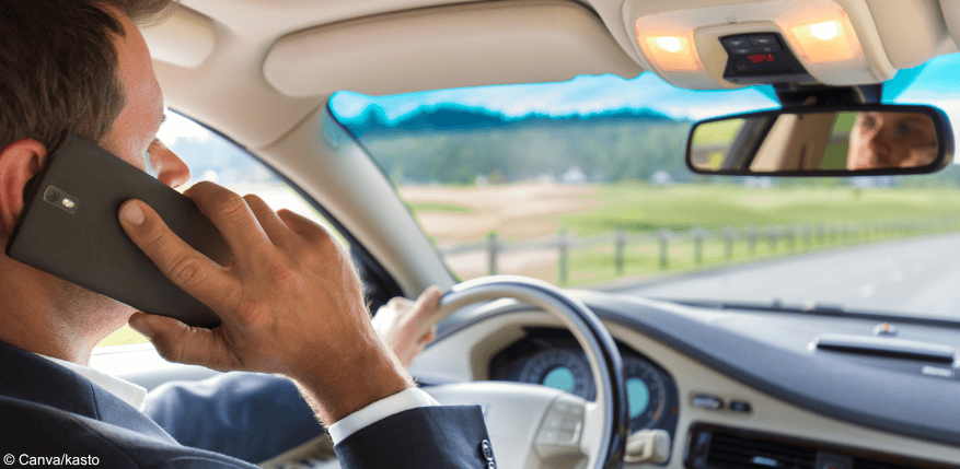 Ein Mann telefoniert mit seinem Handy am Ohr, während er Autofährt: Die Handynutzung beim Autofahren kann 100 € kosten.