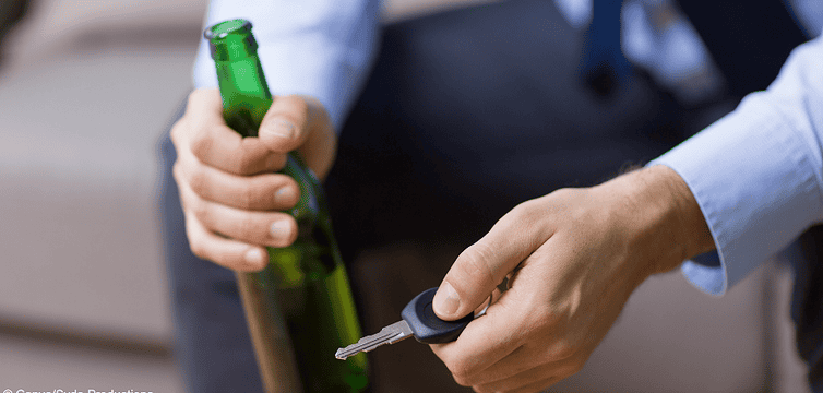 Person mit Alkohol und Autoschlüssel. Gibt es Schmerzensgeld, falls es zu einem Unfall kommt?