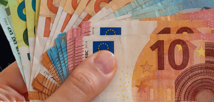Eine Hand mit hunderten Euros, um Zwangsgeld zu bezahlen.