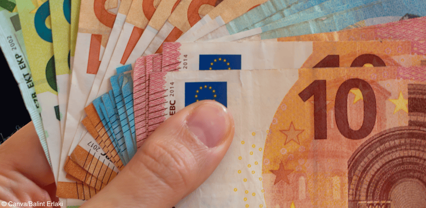 Eine Hand mit hunderten Euros, um Zwangsgeld zu bezahlen.