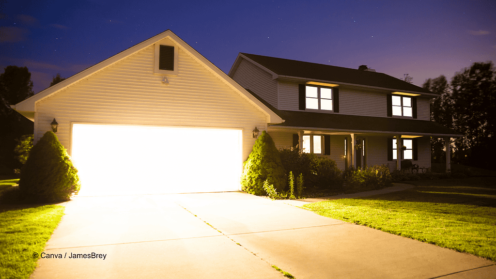 Einfamilienhaus mit Carport daneben. Aus dem Carport kommt sehr helles Licht, um die Lichtimmission der Beleuchtung überspitzt darzustellen.
